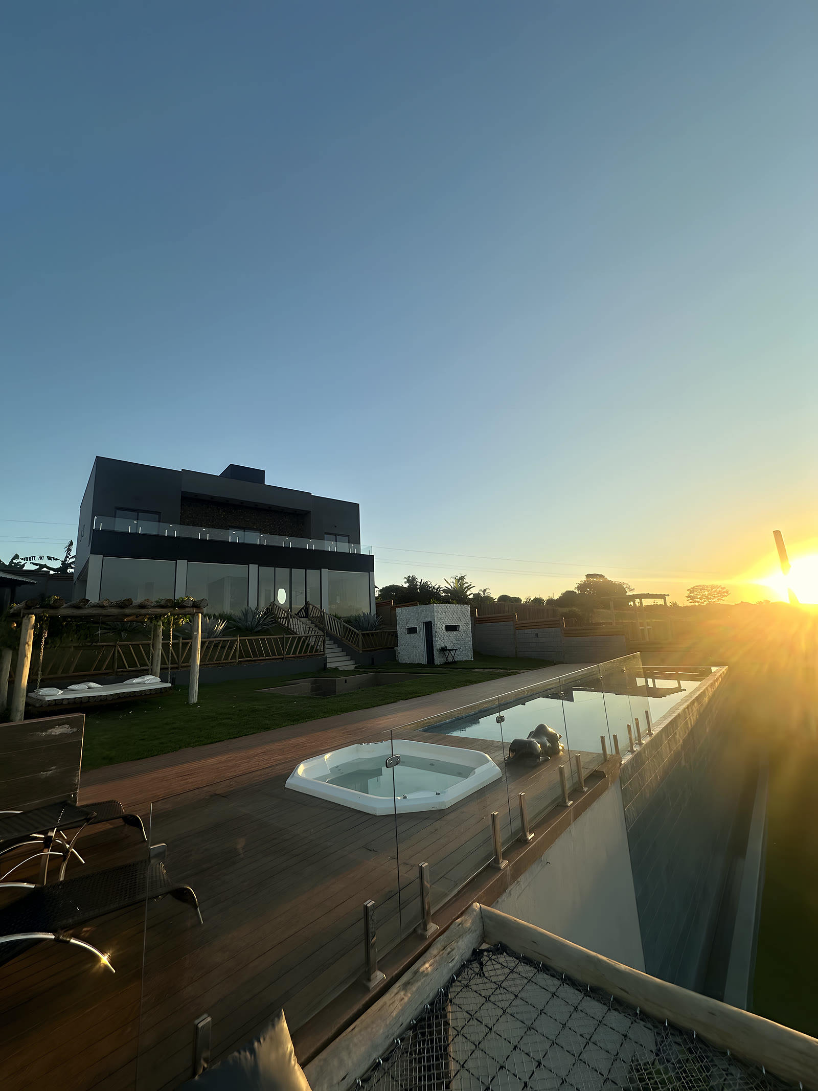 Jacuzzi externa com a casa ao fundo, no fim da tarde