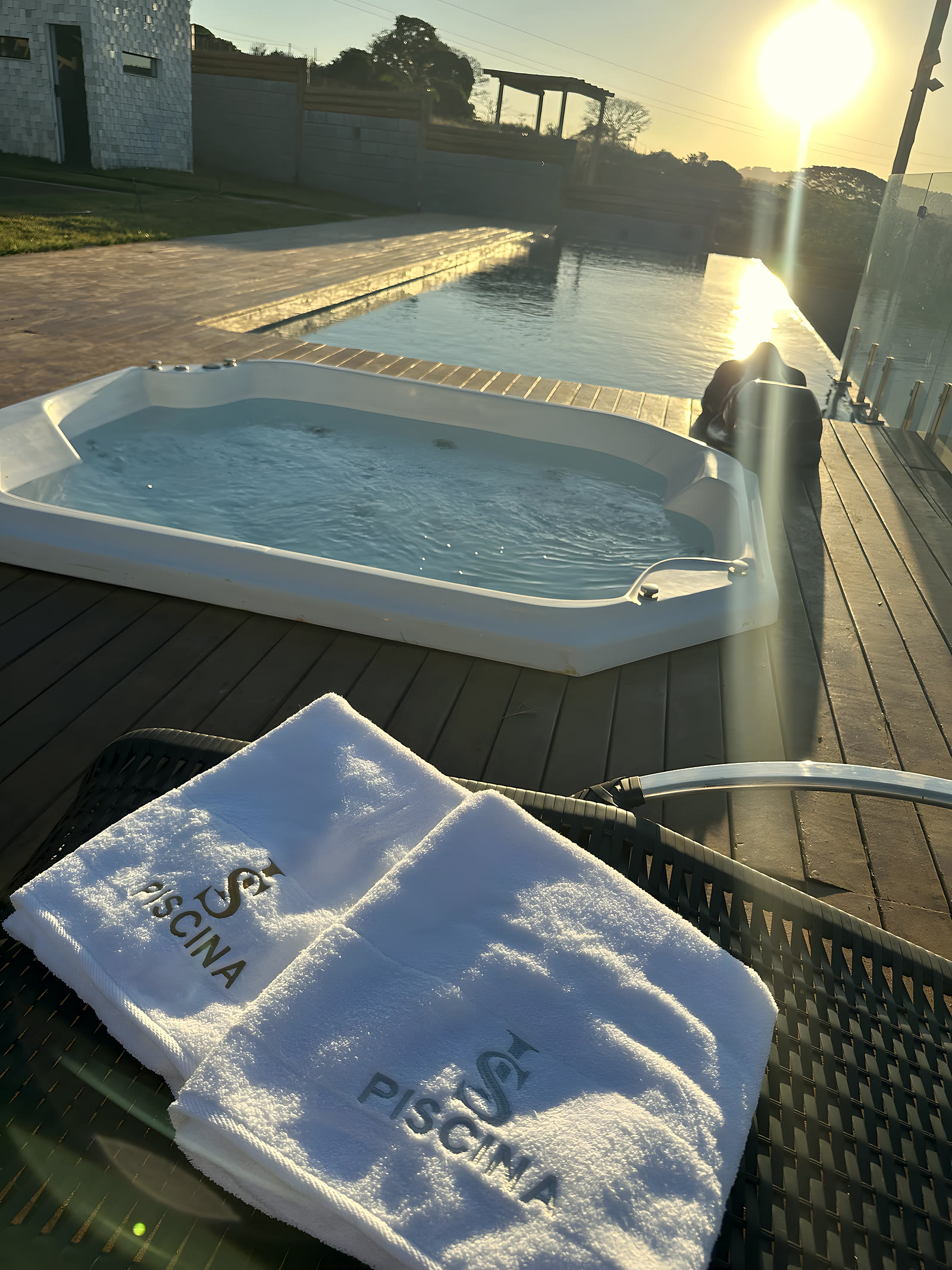 Jacuzzi externa ao lado da piscina, com toalhas bordadas