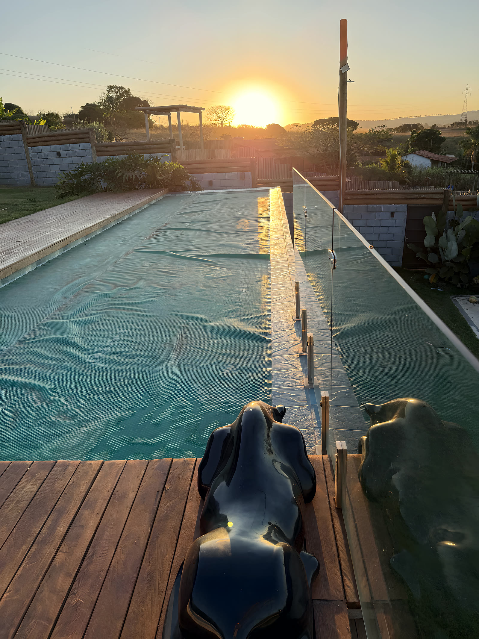 Piscina com borda infinita e escultura ao entardecer