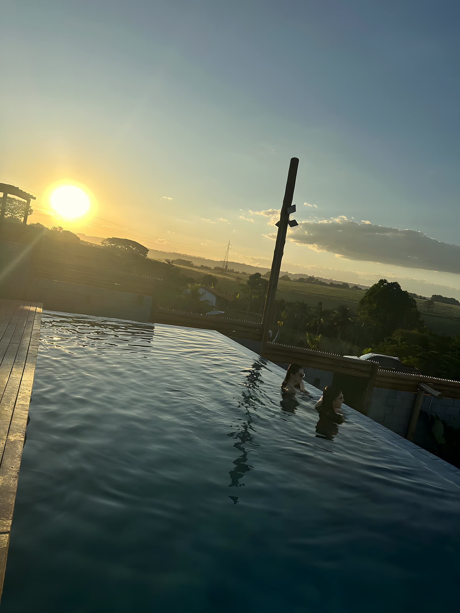 Borda infinita da piscina com o sol se pondo ao fundo